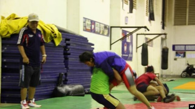 Cambodian Wrestler Chov Sotheara trains with another wrestler while a North Korean Coach watches, Phenom Penh, Cambodia, February 2012.