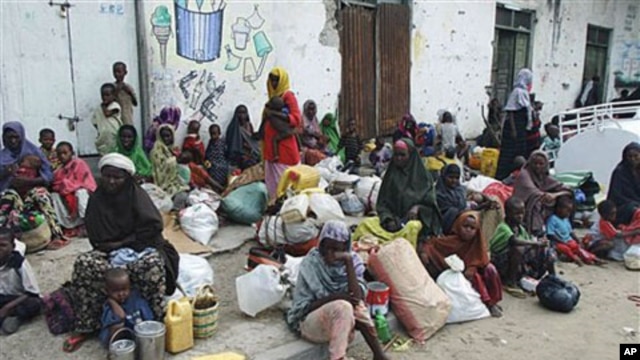Families from the south of the country wait at the side of a street before making their way to a refugee camp seeking food and shelter, in Mogadishu, Somalia, August 3, 2011