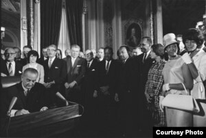 Photograph of President Lyndon Johnson signing the Voting Rights Act as Martin Luther King, Jr., with other civil rights leaders in the Capitol Rotunda, Washington, DC, August 6, 1965. Creative Commons