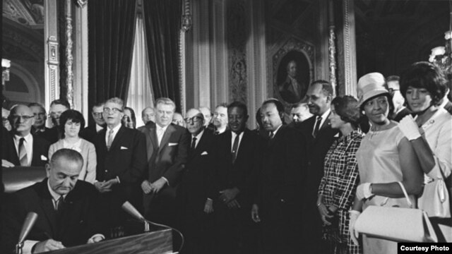 Photograph of President Lyndon Johnson signing the Voting Rights Act as Martin Luther King, Jr., with other civil rights leaders in the Capitol Rotunda, Washington, DC, August 6, 1965. Creative Commons