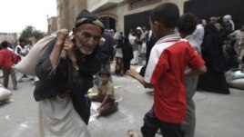 A man carries food aid provided by the Red Crescent Society in Sanaa July 2, 2012.