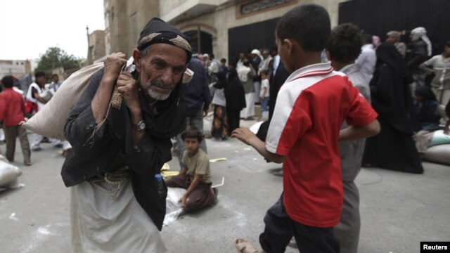 A man carries food aid provided by the Red Crescent Society in Sanaa July 2, 2012.