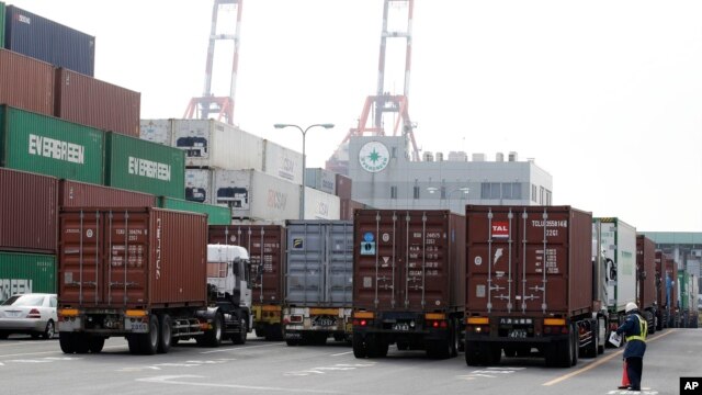 A port security guard stands near containers piled up at a port in Tokyo, January 24, 2013.