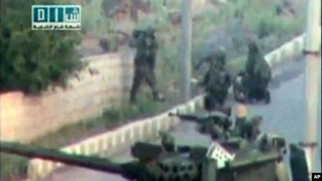 Soldiers take up position near a tank on a street in a location given as Daraa on April 25, 2011, in this still image taken from an amateur video.