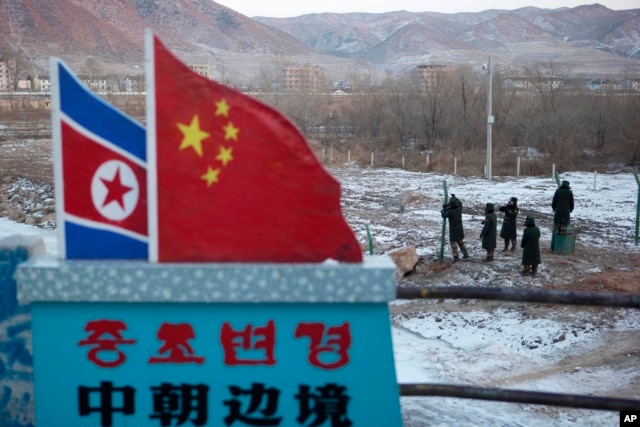 FILE - A Chinese-built fence near a concrete marker depicting the North Korean and Chinese national flags with the words "China North Korea Border" at a crossing in the Chinese border town of Tumen in eastern China's Jilin province.