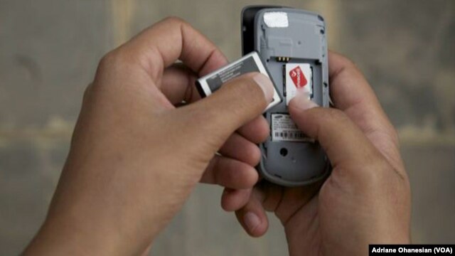A mobile phone user in Juba, South Sudan removes his battery to check his SIM card, which had to be registered by February 28. (VOA)