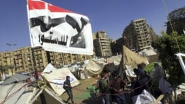 Anti-Mursi protesters sit outside their tents, below a flag that reads, "No, to Constitution" at Tahrir Square in Cairo December 10, 2012. The Egyptian government has given the military the authority to arrest civilians to help safeguard a constitutional 