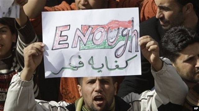 A Libyan protester holds up a sign against Libyan Leader Moammar Gadhafi during a demonstration, in Tobruk, Libya, February 23, 2011.