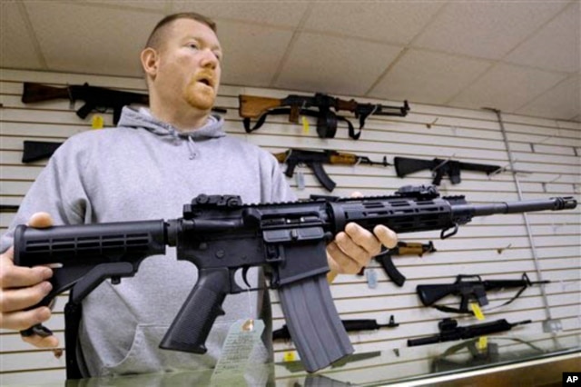 FILE - The owner of a gun shop holds one of the assault rifles his store sells.