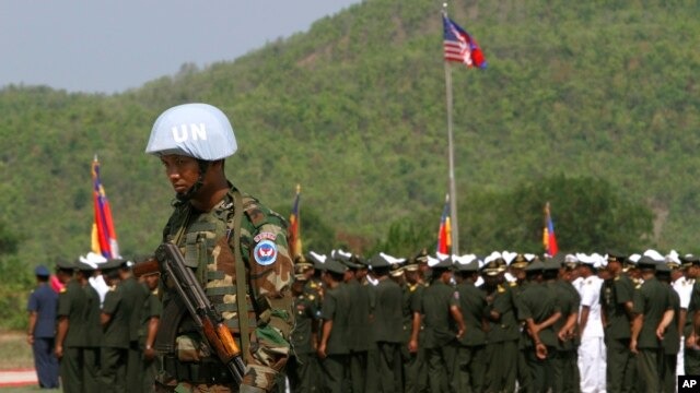 A Cambodian army soldier, foreground, wears a U.N. helmet while standing guard during a U.S.-backed peacekeeping exercise dubbed "Angkor Sentinel 2014" at the Cambodian tank command headquarters in Kampong Speu province, 60 kilometers (37 miles) west of Phnom Penh, Cambodia, Monday, April 21, 2014. 