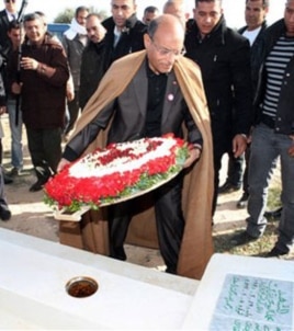 Tunisian President, Moncef Marzouki places flowers at the tombstone of Mohamed Bouazizi, a 26-year-old who set himself alight on Dec. 17, 2010