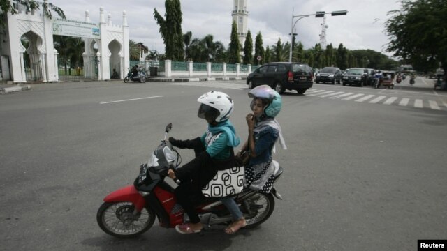 Dua perempuan Aceh berboncengan di atas sepeda motor dekat Mesjid Baiturrahman di Banda Aceh (3/1). (Reuters/Junaidi Hanafiah) 