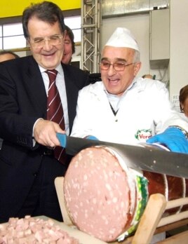 Romano Prodi slices a large Italian sausage while running for office in Bologna, Italy in 2006.