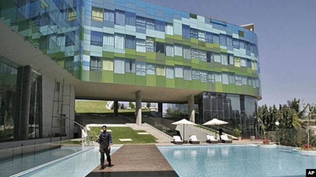 A staff member of Vivanta By Taj, a Tata group hotel, walks past the swimming pool at a luxury hotel in Bangalore, India. People in cities like Jaipur want international experiences similar to the kind available in big cities. (2009 File) 