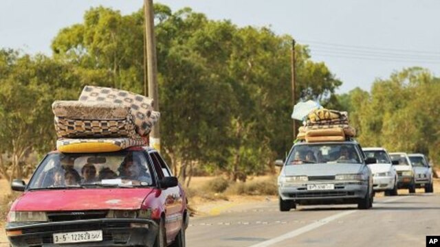 Families fleeing from the fighting between pro-Gaddafi and anti-Gaddafi forces drive pass Khamseen Gate, 50 km (31.1 miles) east of Sirte, October 1, 2011.