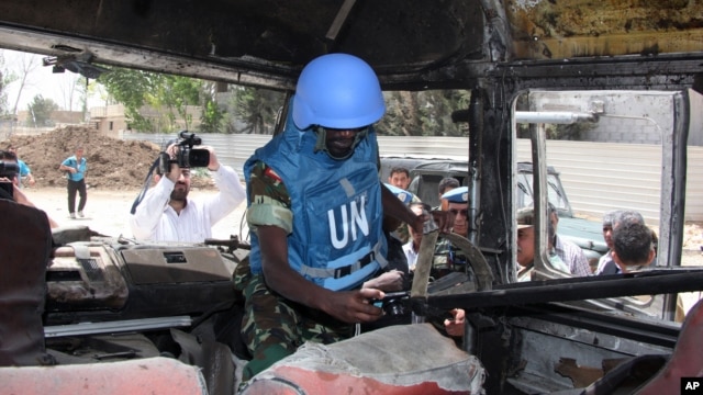 A U.N. observer takes pictures of a military bus that was damaged by a roadside bomb, at al-Bahdaliyah area, near Damascus, Syria, Wednesday, May 23, 2012. 