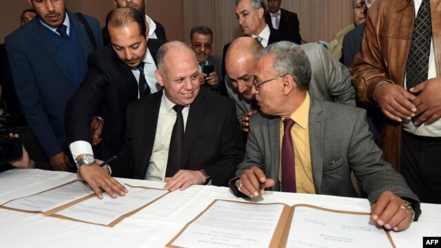 FILE - Awad Mohammed Abdul-Sadiq (L), of the Tripoli-based General National Congress (GNC), and Ibrahim Fethi Amish, from the internationally recognized House of Representatives, sign agreement on ending the political deadlock in Libya, Dec. 6, 2015.