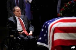 El exsenador Bob Dole, de 95 años de edad, recibió ayuda para levantarse de su silla de ruedas y saludó el féretro del fallecido expresidente George H. W. Bush.
