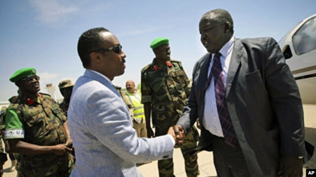 Uganda's Acting Foreign Affairs Minister Okello Oryem (R) is greeted by Somali Deputy Prime Minister and Minister for Defense Hussein Arab Issa upon his arrival at Mogadishu Airport, February 13, 2012