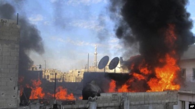 In this Feb. 22, 2012 citizen journalism image provided by the Local Coordination Committees in Syria, flames rise from a house from Syrian government shelling, at Baba Amr neighborhood in Homs province.