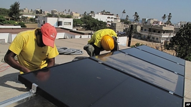 Prosolia technicians Mamadou Ba, left, and Mouhamed Diedhiou install solar panels on a vocational school in Dakar, Senegal, Dec. 1, 2011.