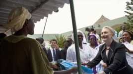 U.S. Secretary of State Hillary Clinton (R) gives a mosquito net for malaria prevention to a local woman during a tour of the Philippe Senghor Health Center in Dakar, Senegal, August 1, 2012.