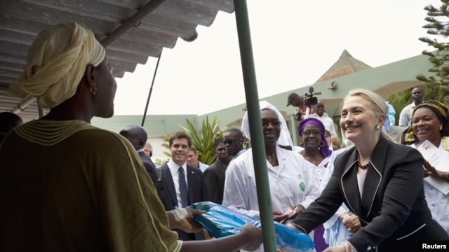 U.S. Secretary of State Hillary Clinton (R) gives a mosquito net for malaria prevention to a local woman during a tour of the Philippe Senghor Health Center in Dakar, Senegal, August 1, 2012.