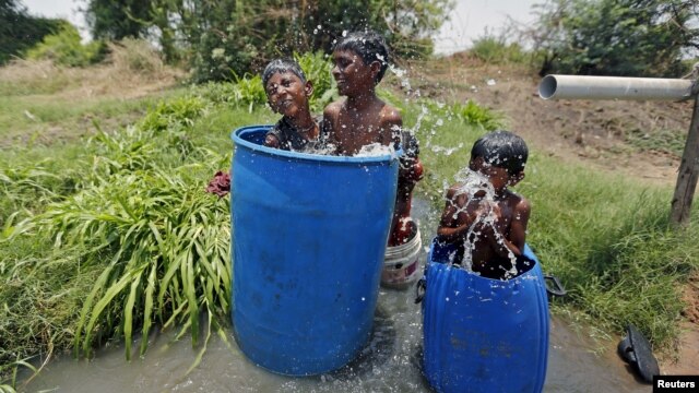 Anak-anak di Ahmedabad, India mendinginkan diri di dalam bak plastik (28/5). Jumlah korban tewas akibat gelombang panas di India telah bertambah menjadi lebih dari 1.800 orang, kata para pejabat hari Jumat (29/5). (Foto: REUTERS/Amit Dave).