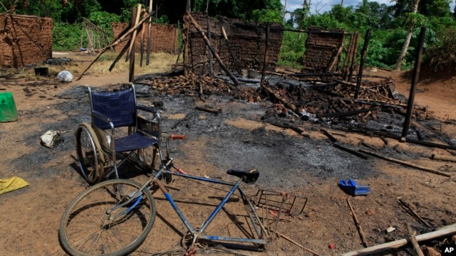 The wheelchair of Amelie Vlonhou, whose body lies nearby, sits beside a burned hut at the Dedjan campsite, near the banks of the Cavally River in western Ivory Coast, May 26, 2011. 