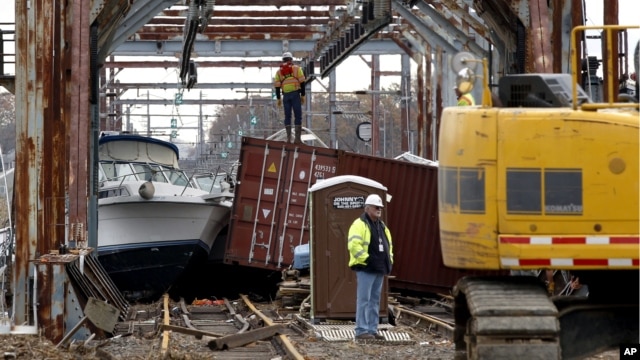 Workers try to clear boats and debris from the New Jersey Transit Morgan draw bridge in South Amboy, New Jersey after Monday's storm surge from Sandy pushed boats and cargo containers onto the train tracks, October 31, 2012.
