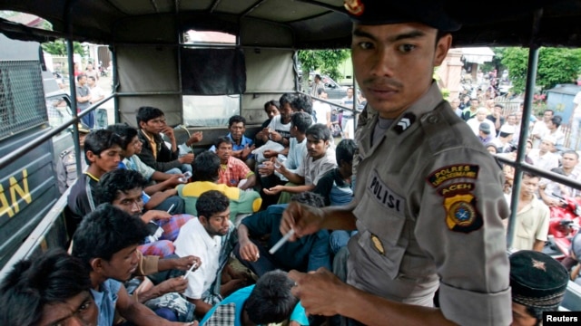 An Indonesian policeman guards ethnic Rohingya refugees from Myanmar as they wait inside a police truck for identification by immigration personnel in Lhokseumawe, Feb. 27, 2013. 