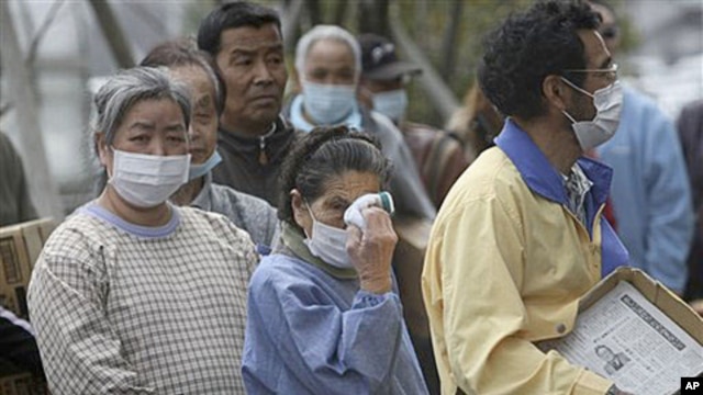 An elder woman wipes her eyes in long lines for food at an evacuation shelter in Koriyama, Fukushima prefecture, Japan, April 2, 2011