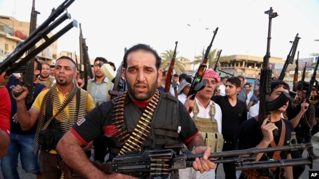 FILE - Iraqi Shi'ite tribal fighters deploy with their weapons while chanting slogans against the al-Qaida-inspired Islamic State of Iraq and the Levant, in Baghdad's Sadr City, Iraq, June 13, 2014.