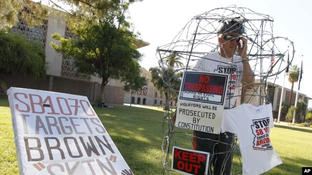 Surrounded by barbed wire, Jorge Mendez joins others from Promise Arizona to protest the upcoming U.S. Supreme Court decision on Arizona's immigration law SB1070 at a vigil set up in front of the Capitol in Phoenix,June 22, 2012.