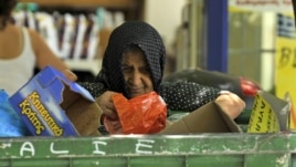A woman collects goods from a garbage bin outside a supermarket in Thessaloniki, Greece, July 3, 2012. 