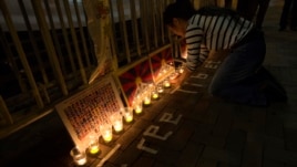 A protester arranges candles during a candlelight vigil outside a China Liaison Office in Hong Kong, February 13, 2013.