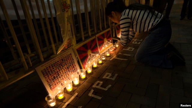 A protester arranges candles during a candlelight vigil outside a China Liaison Office in Hong Kong, February 13, 2013.
