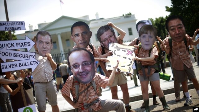 Militan Oxfam activist ak mask nan figi yo nan yon manifestasyon kont lidè G8 yo devan Lamezon Blanch Washington, DC 17 me, 2012.