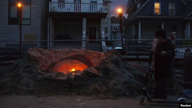 Shane Decarolis stands with his scooter next to a fire outside his home on Beach 91st street in the Rockaways section of the Queens borough of New York, November 3, 2012. 