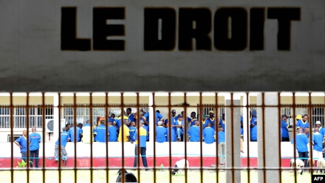Prisoners are seen at the Makala prison in Kinshasa from behind the bars of the windows of a court room,  on December 18, 2012.