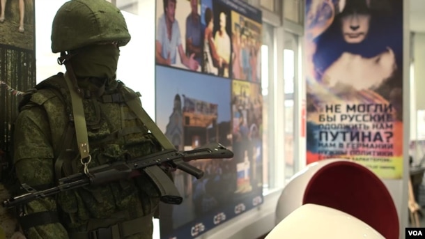 A mannequin soldier holding a rifle and representing the "little green men" whom Russia dispatched to help annex Ukraine's Crimea overlooks the office of pro-Kremlin youth group SET (Network). (VOA video screengrab)