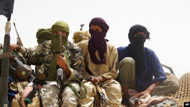 Fighters from the Islamist group Ansar Dine stand guard during the handover of a Swiss female hostage for transport by helicopter to neighboring Burkina Faso in the desert outside Timbuktu, Mali, April 24, 2012. 