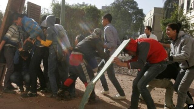 Egyptian protesters protect themselves behind makeshift shields during clashes with army troops near Tahrir Square in Cairo, Egypt, Dec. 18, 2011.