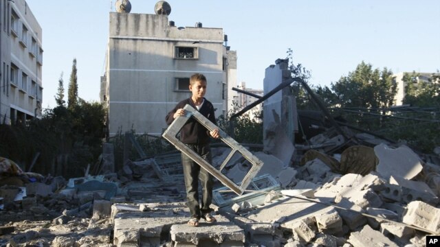 A Palestinian boy holds a window pane taken from a damaged house hit in an Israeli strike, in Gaza City, November 15, 2012.s