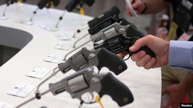 A man holds a gun in the exhibit hall of the George R. Brown Convention Center, the site for the National Rifle Association's (NRA) annual meeting in Houston, Texas, May 3, 2013.