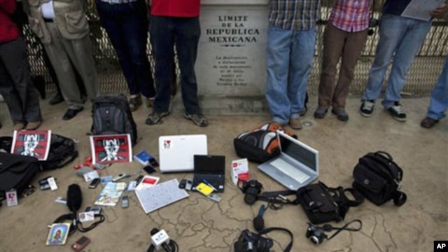 Members of the press stand by their working tools as they protest violence against journalists at the border by a sign that reads in Spanish "Limit of the Mexican Republic" in Tijuana, Mexico, 7 Aug 2010