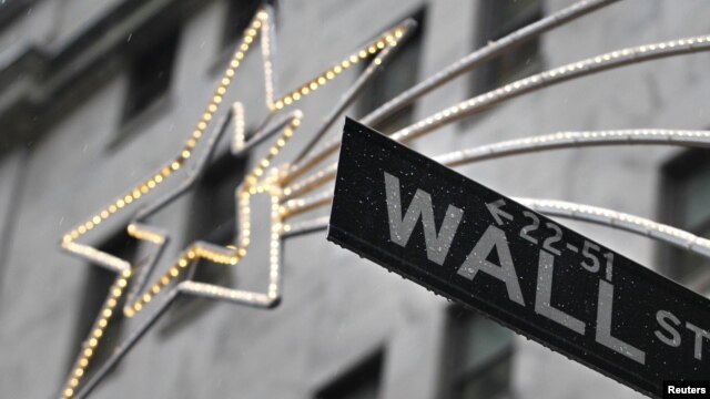 A holiday decoration is seen over Wall St. sign outside the New York Stock Exchange, November 27, 2012.