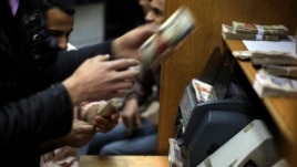 FILE - Egyptians count money at a currency exchange office in downtown Cairo, Jan. 2, 2013. 