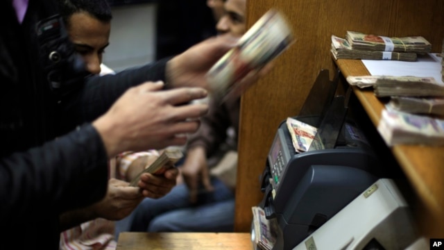 FILE - Egyptians count money at a currency exchange office in downtown Cairo, Jan. 2, 2013. 