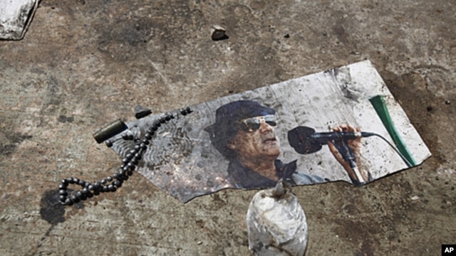 A picture of ousted Libyan leader Muammar Gadhafi is seen on the ground of the ransacked Bab al-Aziziya compound in Tripoli, August 26, 2011